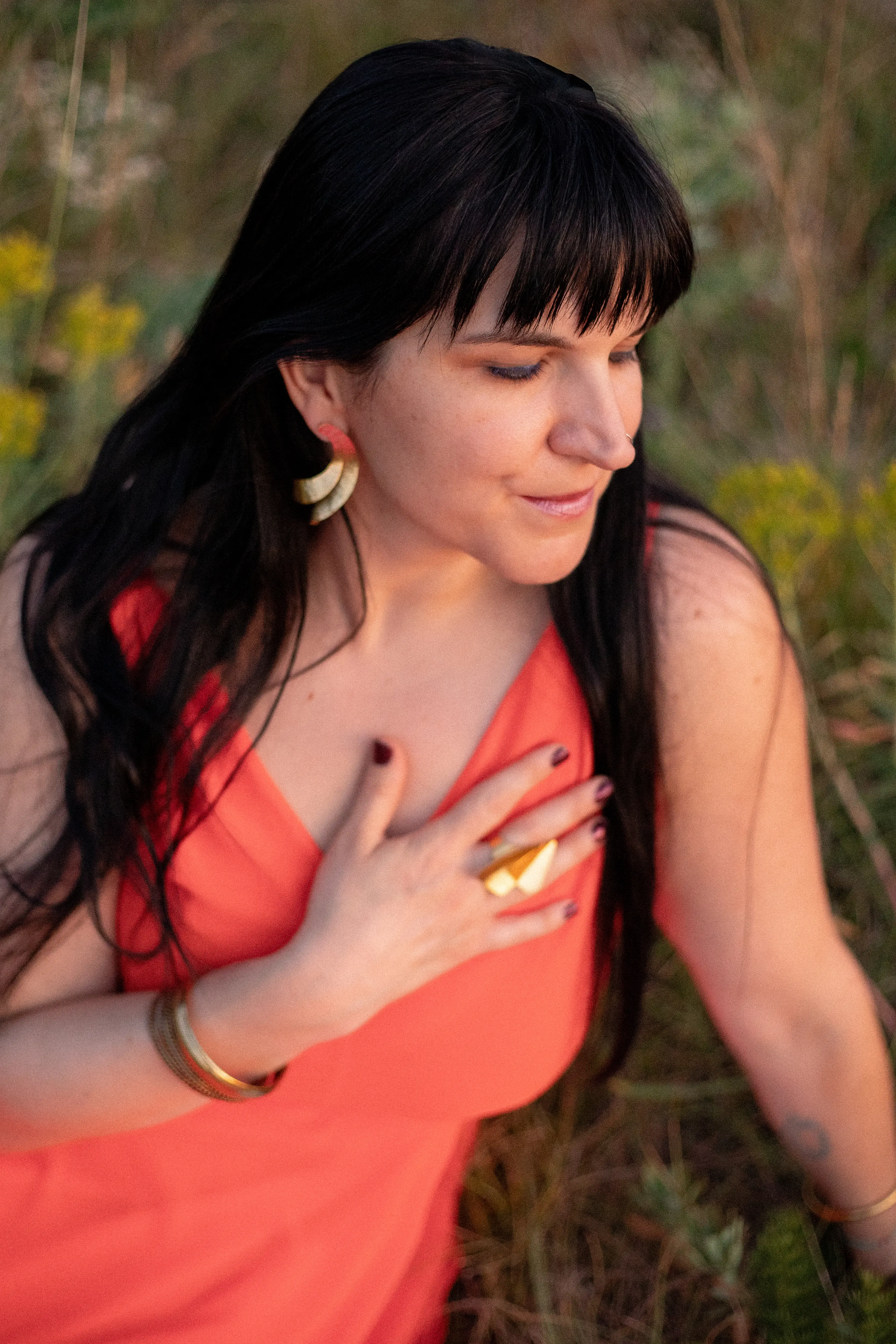 Adrienne with her hand resting over her heart, eyes closed, golden hour light